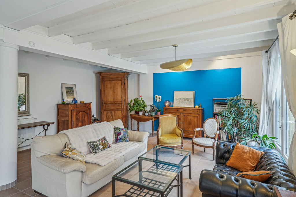 Vue général d'un séjour rénové avec un bleu lumineux peint sur un mur comme un cadre pour mettre en avant les anciens meubles situés dans le séjour.